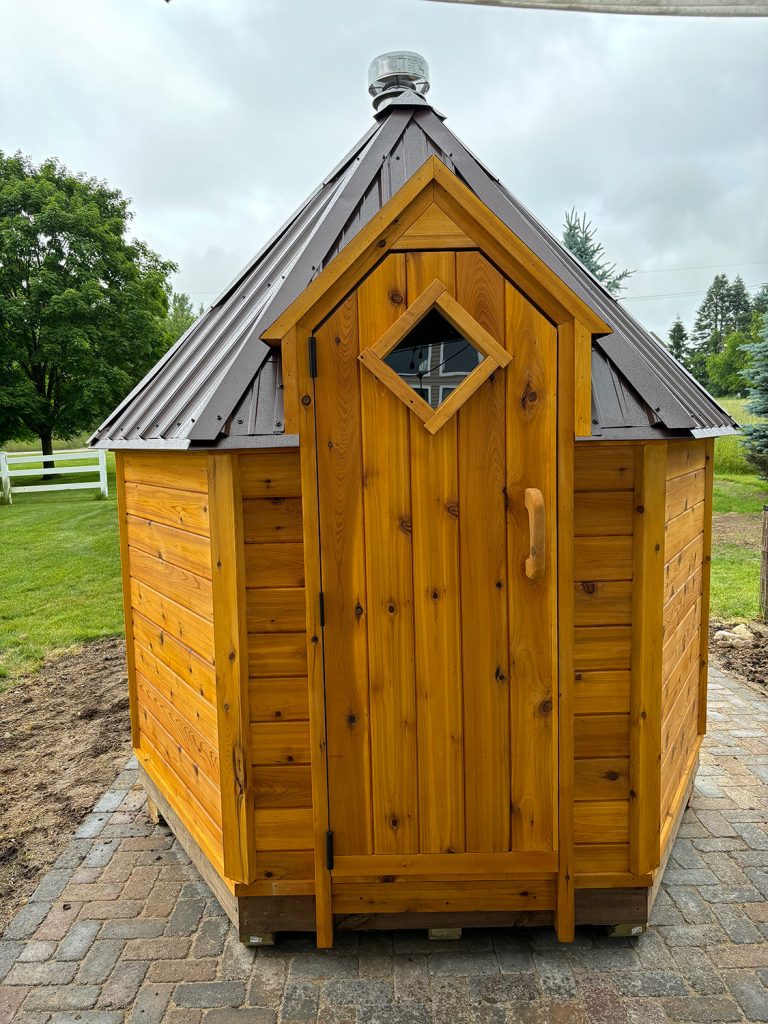 Hexagonal sauna with brown metal roof.